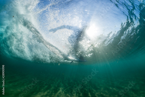 dramatic surfer silhouette underwater riding a huge wave