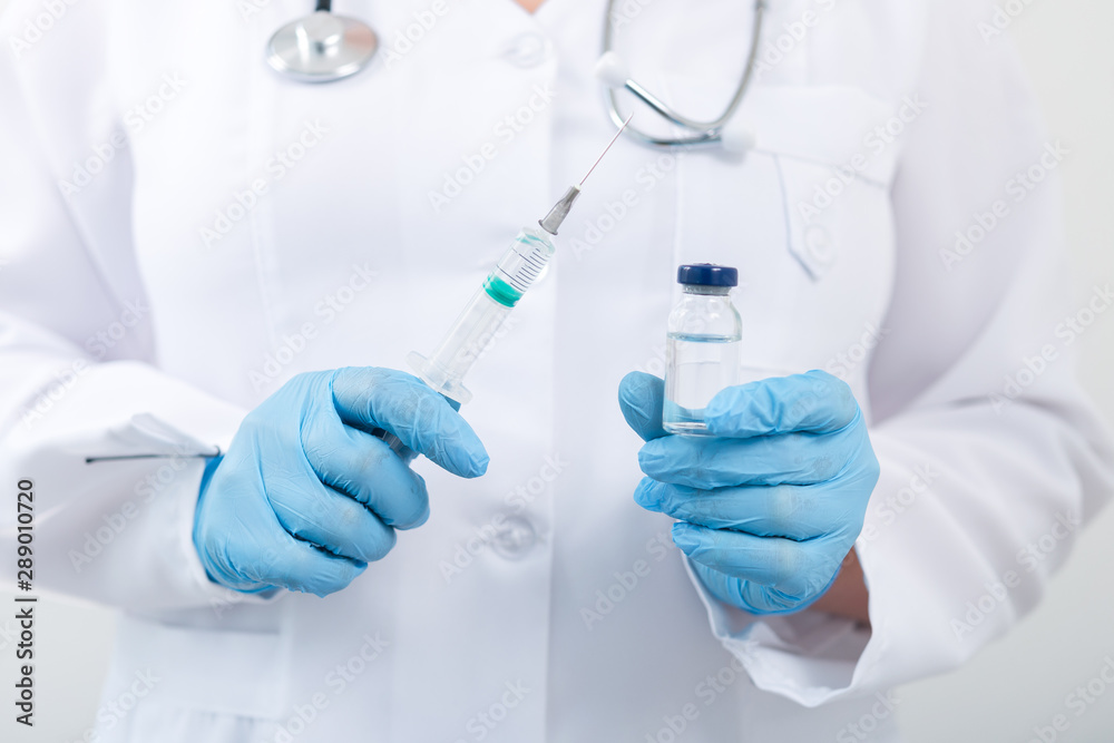 Fototapeta premium Female doctor holding flu vaccine in hands in clinic room