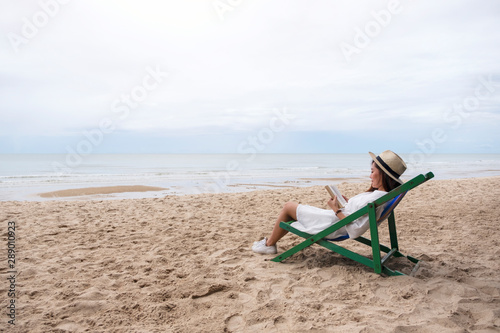 A beautiful woman lying down and reading book on the beach chair with feeling relaxed