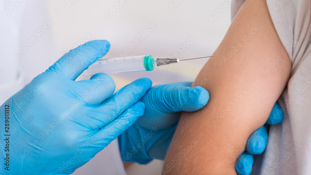 Pediatrician give syringe injecting flu vaccination in arm little boy Pediatrician give syringe injecting flu vaccination in arm little boy