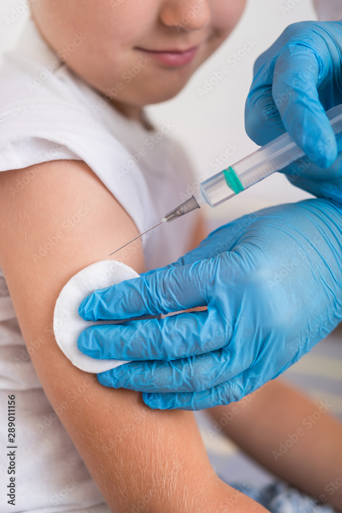 Doctor give injection of vaccine to boy at home