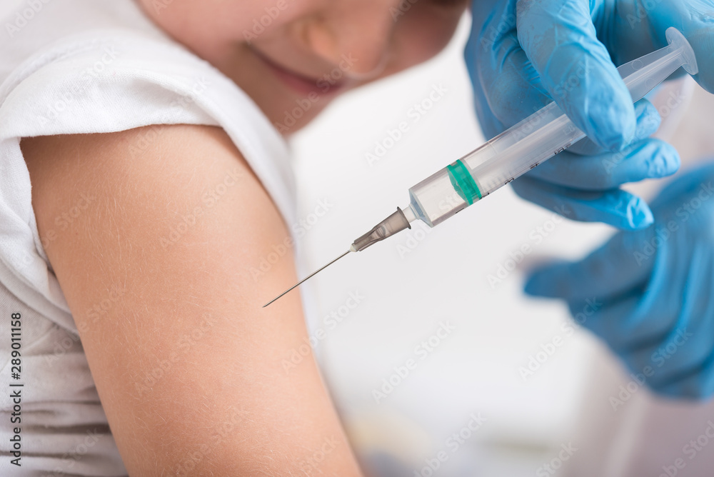 Doctor give injection of vaccine to boy at home Doctor give injection of vaccine to boy at home