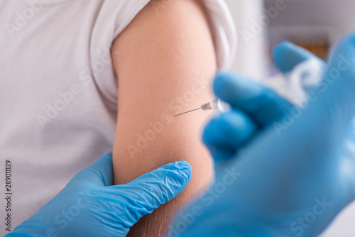 Doctor give injection of vaccine to boy at home