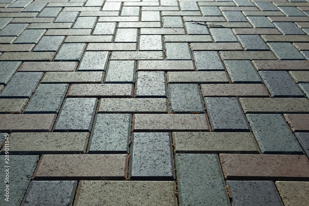 Background - colorful cobblestone pavement of the new paving stones. Diminishing perspective. Backlight.