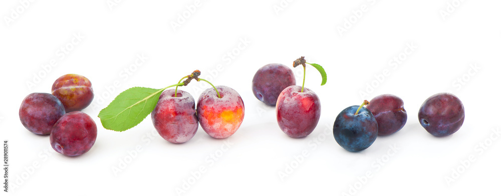 Ripe plums with leaves close up on white background