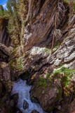 Klamm in Felsen mit rauschendem Wildwasserbach und Nadelbäumen am Rand