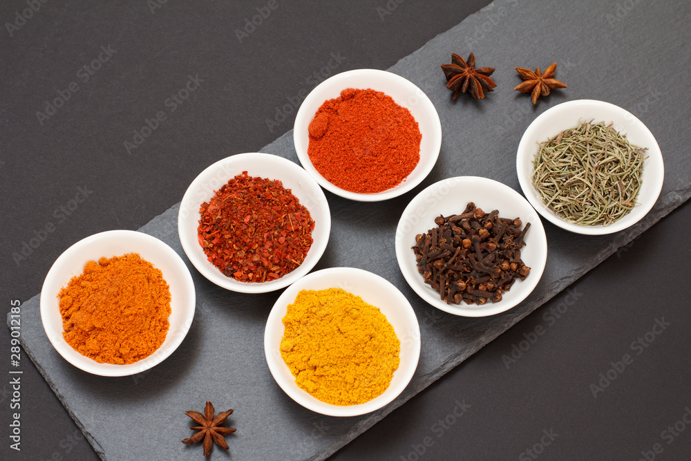 Various ground spices and herbs on stone cutting board. Various ground spices and herbs on stone cutting board.