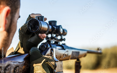 Shooter sighting in the target. The man is on the hunt. Hunt hunting rifle. Hunter man. Hunting period. Male with a gun. Close up. Hunter with hunting gun and hunting form to hunt. Hunter is aiming. © Yevhen