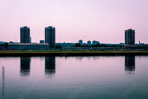 The North Woolwich skyline, with the tower blocks reflected on Thames canal. North Woolwhich is an industrialised settlement hemmed in by the King George V Dock and the River Thames, in East London,UK photo