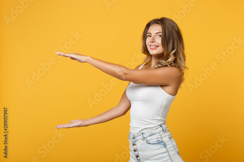 Charming young woman girl in light casual clothes posing isolated on yellow orange wall background. People lifestyle concept. Mock up copy space. Gesturing demonstrating size with vertical workspace.