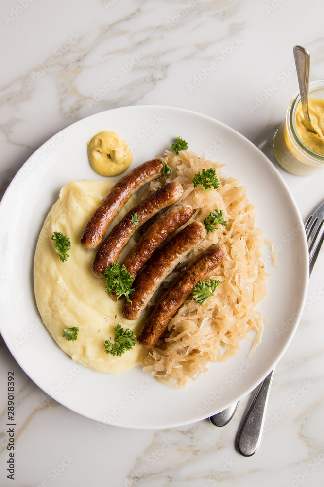 Kleine Bayrische Nürnberger Rostbratwürste mit Sauerkraut, Kartoffelpüree und Senf auf Marmor Tisch Hintergrund