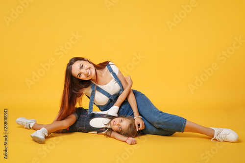 Woman in light clothes have fun with cute child baby girl 4-5 years old. Mommy little kid daughter isolated on yellow background studio portrait. Mother's Day love family parenthood childhood concept.