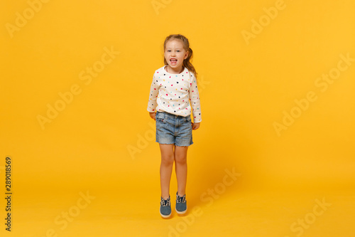 Little cute child kid baby girl 4-5 years old wearing light denim clothes isolated on pastel yellow wall background, children studio portrait. Mother's Day, love family, parenthood childhood concept.