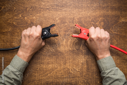 Hands holding battery charging clamps