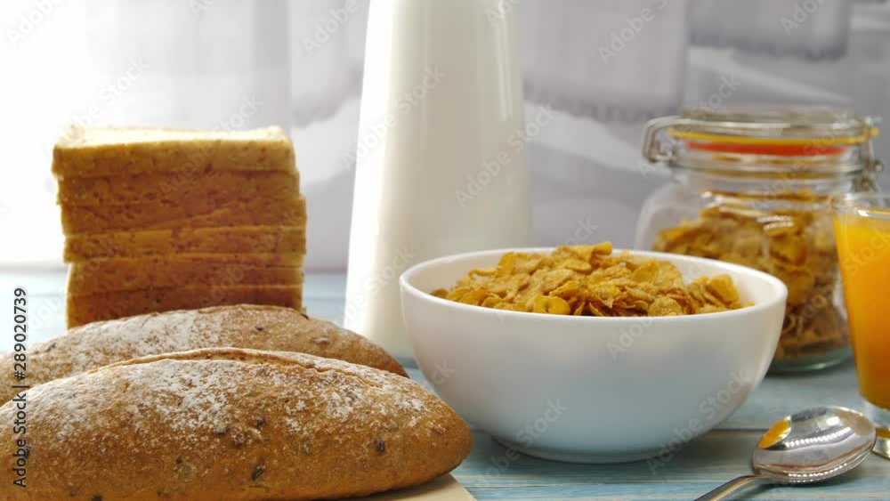 Breakfast served with orange juice, croissants, cereals and milk on the table wooden in the morning sunshine. Healthy food. Dolly shot slide Breakfast served with orange juice, croissants, cereals and milk on the table wooden in the morning sunshine. Healthy food. Dolly shot slide