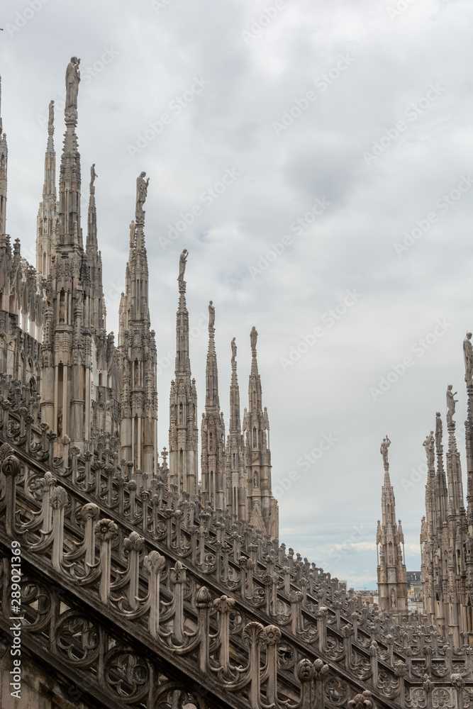 A roof top view of Milan Cathedral, Duomo di Milano - the cathedral church of Milan, Lombardy, Italy. Dedicated to the Nativity of St Mary. Close-up view of Milan Cathedral sculpture