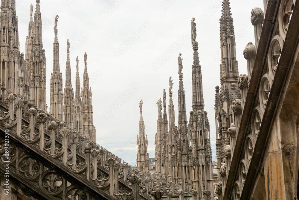 A roof top view of Milan Cathedral, Duomo di Milan. Close-up view of Milan Cathedral sculpture. The roof of the cathedral with forest of openwork pinnacles and spires