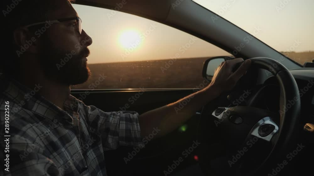 A man rides his car on the sunset background, slow-motion 4k shot A man rides his car on the sunset background, slow-motion 4k shot