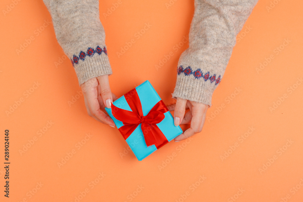 Woman hands holding gift box on orange background