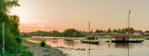 wooden riverboats ona calm Loire River at sunset in the French countryside near Orleans