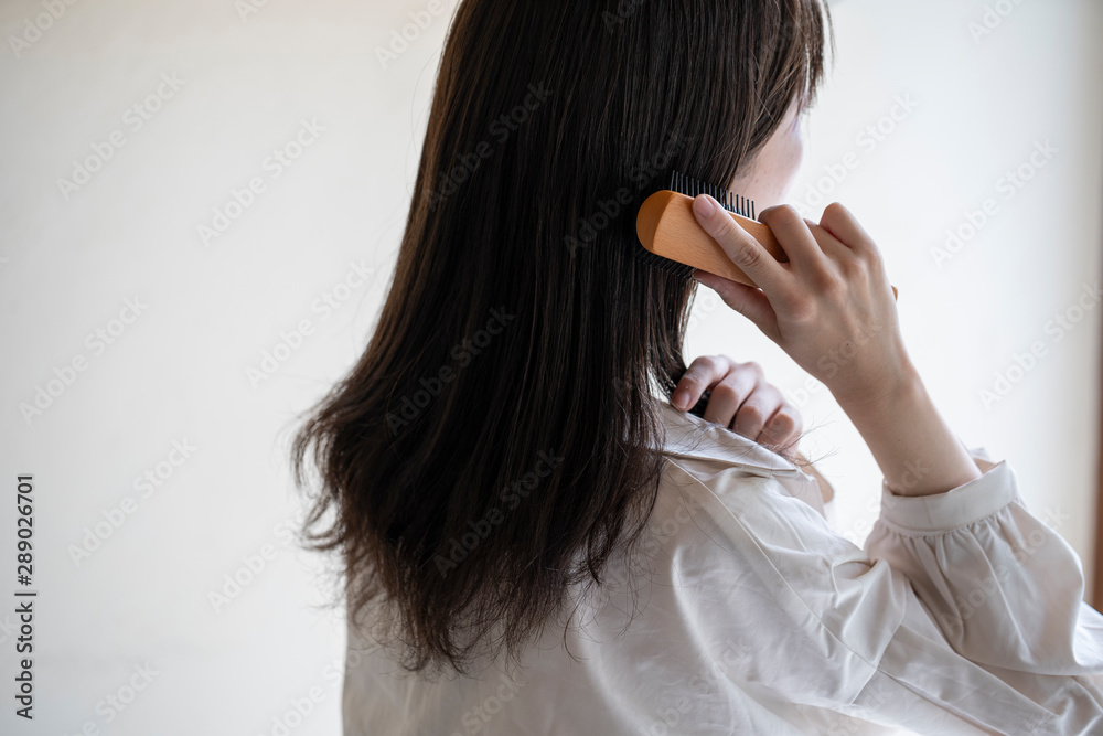 Naklejka premium 髪の毛をブラシで解く女性の後ろ姿