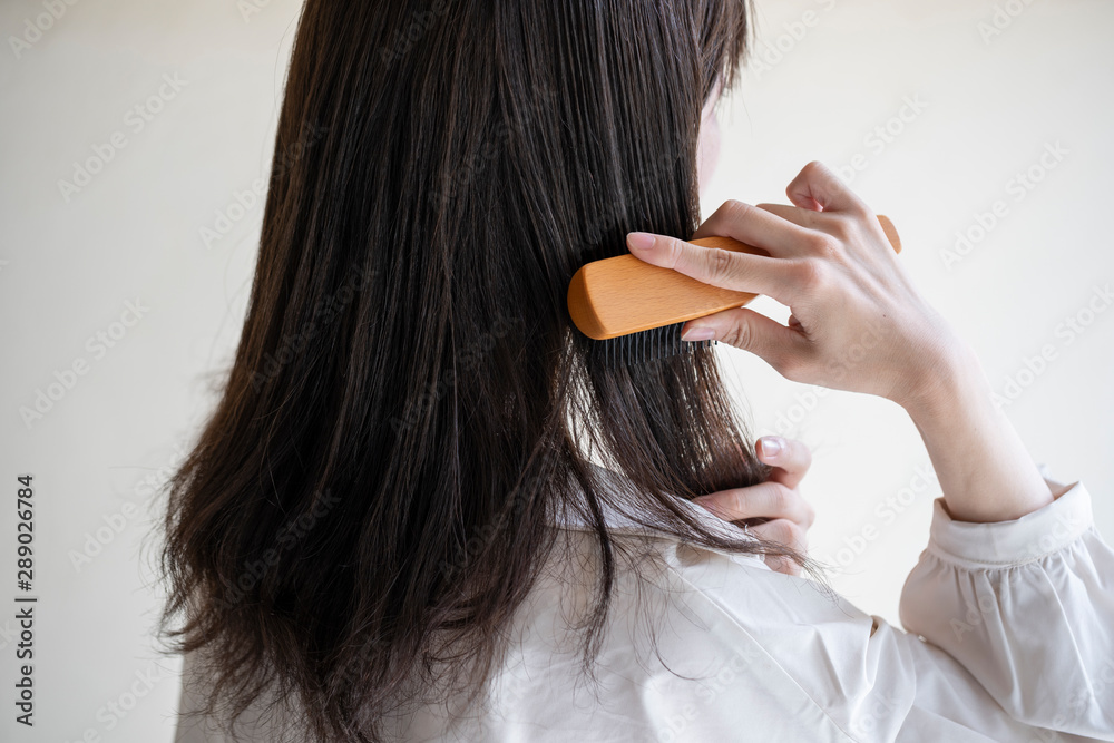Fototapeta premium 髪の毛をブラシで解く女性の後ろ姿
