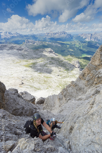attractive female climbers on a steep Via Ferrata in the Italian Dolomites