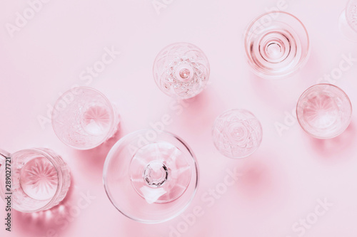 Many empty glasses on pink background. Top view, flat lay