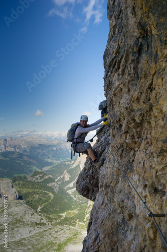 attractive female climber on a steep Via Ferrata in the Italian Dolomites