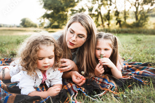 Blonde mother with two cute daughters are walking and having fun outdoors. Stylish, casual clothes.
