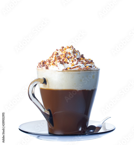 Cappuccino coffee, with whipped cream and ground cinnamon in a glass mug, on a saucer.With ground nut. Iron spoon for coffee. Isolate on a white background. The photo.