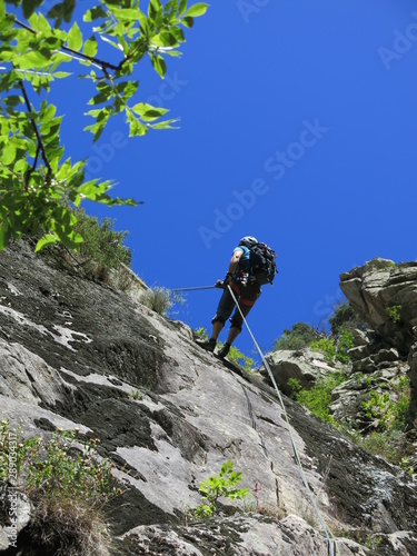 alpiniste en descente en rappel avec corde dans une paroi en montagne après l'escalade