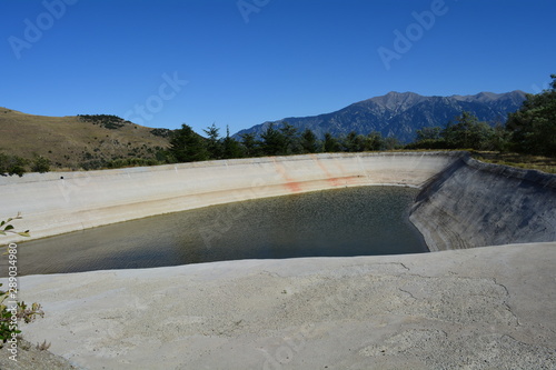 bassin de rétention d'eau pour irrigation vide car sècheresse et manque d'eau en montagne photo