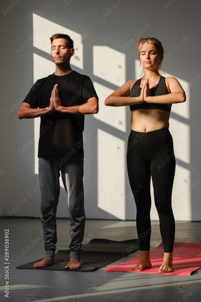 Fototapeta premium Man and women holding hands in namaste gesture, ready to start practicing yoga meditation exercises at group training class 
