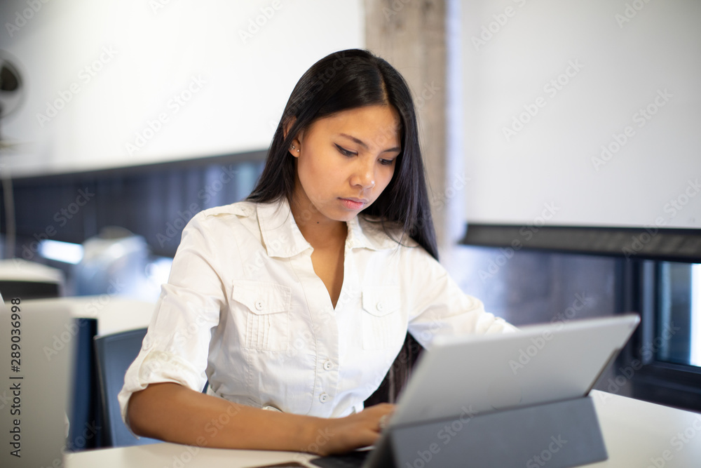 young asian woman working on tablet with white shirt young asian woman working on tablet with white shirt