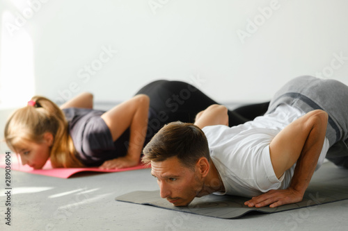 Fitness, stretching practice, group of two working out in sports club, doing easy alternative to Chaturanga Dandasana, half push-up, Caterpillar pose, Ashtanga Namaskara