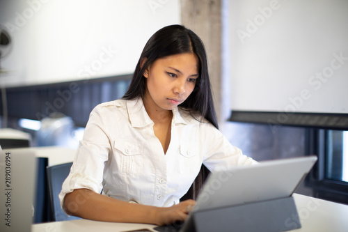 young asian woman working on tablet with white shirt