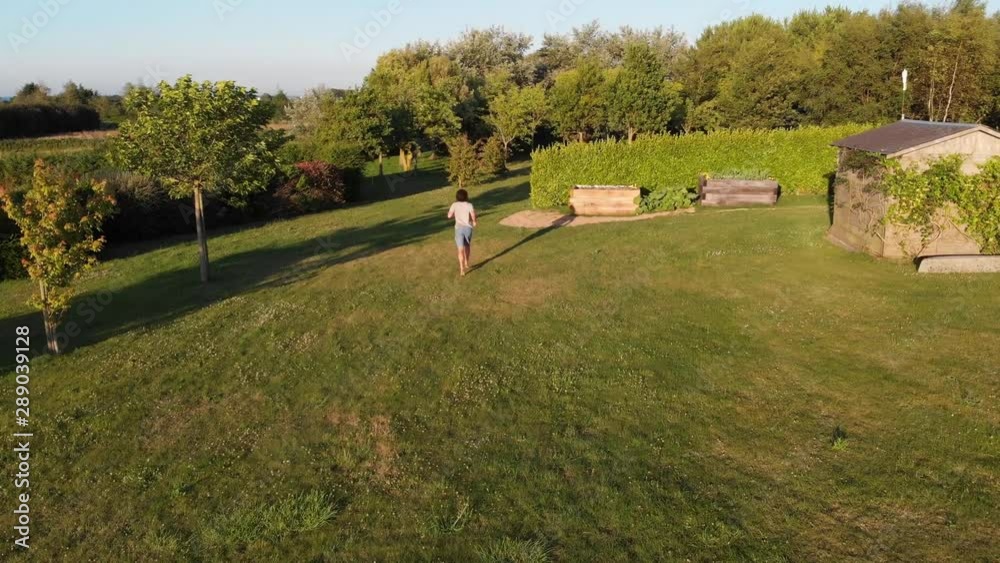 Aerial Drone Shot of Man Running Through a Large Backyard