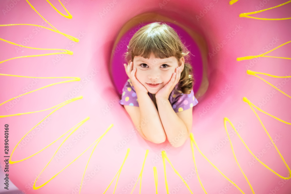 Cute little girl with huge donut. Child is having fun with donut. Tasty food for kids.