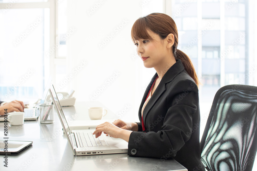 オフィスでデスクワークをする女性 オフィスでデスクワークをする女性