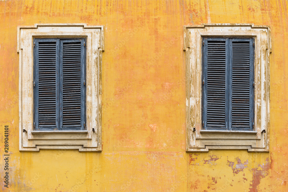 Two windows with wooden jalousie on the old stone wall Two windows with wooden jalousie on the old stone wall