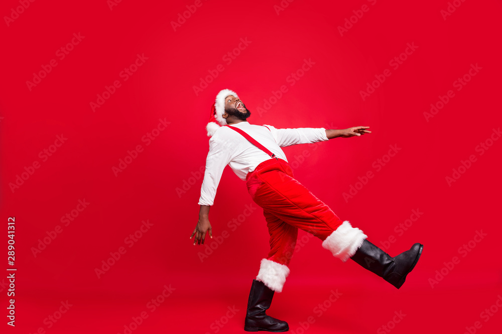 Full body profile side photo of cheerful afro american santa claus laughing moving wearing white jumper isolated over red background