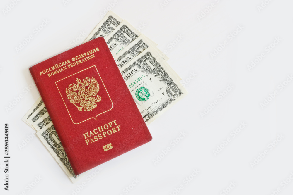 The Russian foreign passport lies on top of one-dollar bills on a light background. Traveling abroad, budget vacation. The Russian foreign passport lies on top of one-dollar bills on a light background. Traveling abroad, budget vacation.