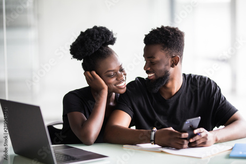 African young man and woman look at phone in office