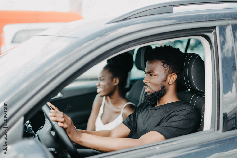 Young african couple in a car on a road trip smiling to camera