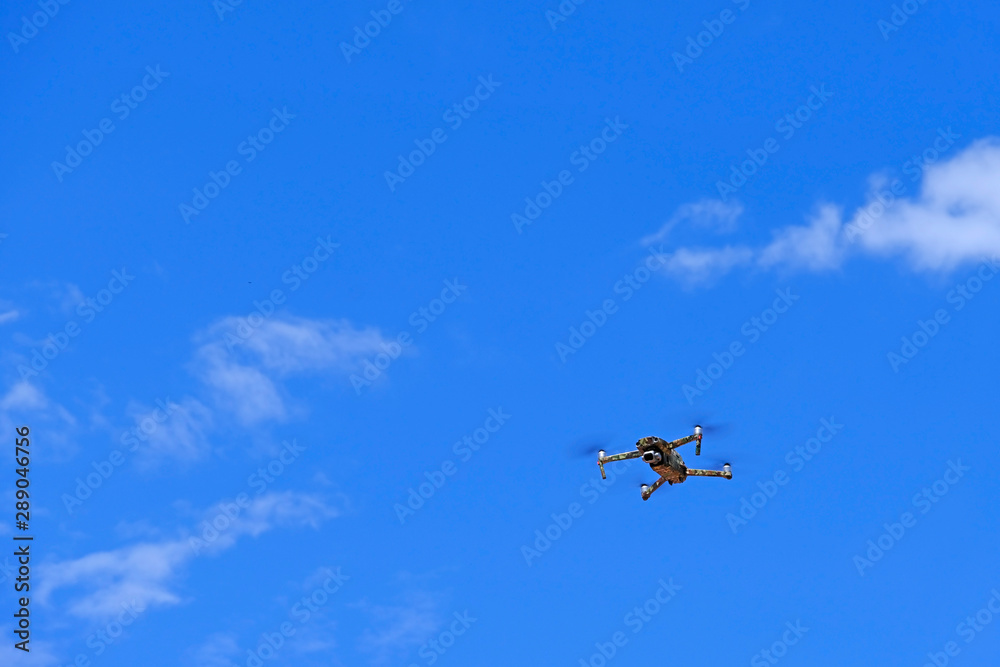 Black drone quadcopter flying on the air for take a photo and video with blue sky background. Black drone quadcopter flying on the air for take a photo and video with blue sky background.