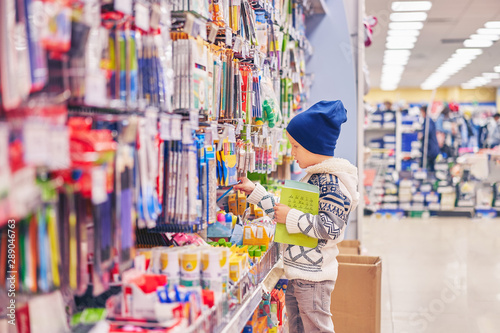 boy chooses pens for school. the child in the store selects the goods. © Aleksandr