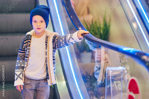 the child goes down on the escalator. boy coddling in the supermarket on an escalator. photo