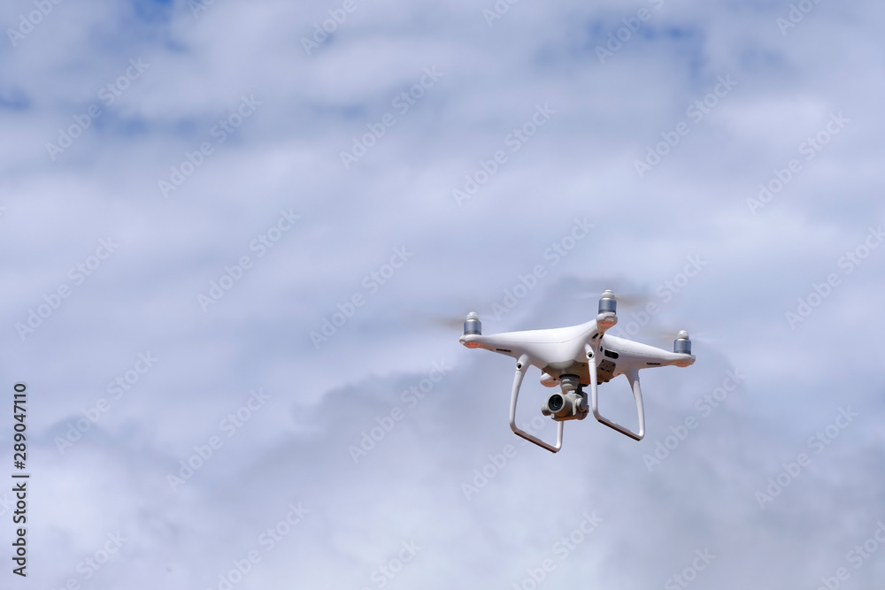 White drone quadcopter flying on the air for take a photo and video with white cloudy background. White drone quadcopter flying on the air for take a photo and video with white cloudy background.