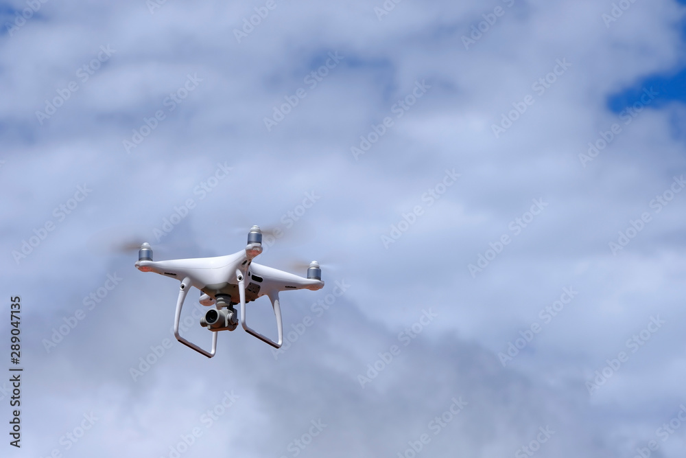 White drone quadcopter flying on the air for take a photo and video with white cloudy background. White drone quadcopter flying on the air for take a photo and video with white cloudy background.